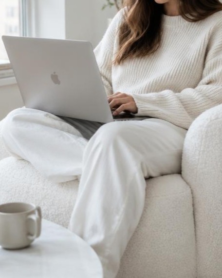Woman working on a laptop in a white boucle armchair